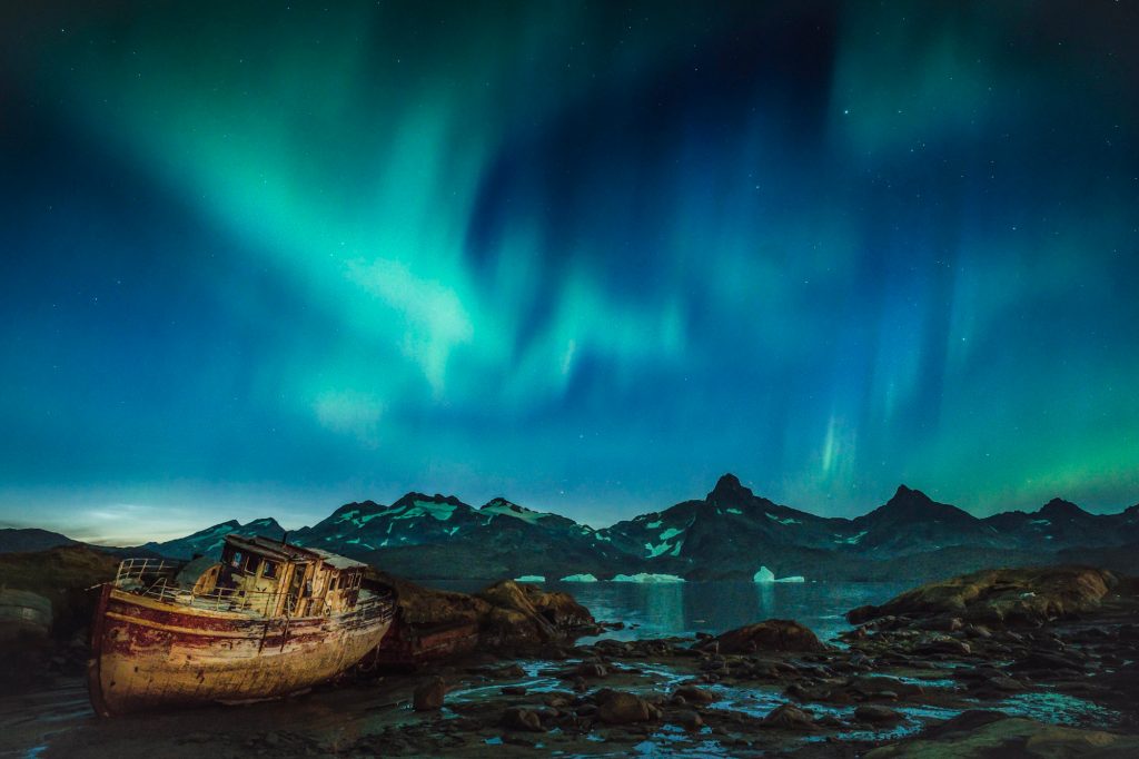 east greenland small boat wreck with aurora istk