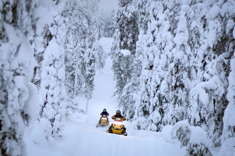 finnish lapland isokenkasiten snowmobiles in forest