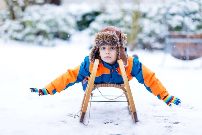 young boy on toboggan in snow istk