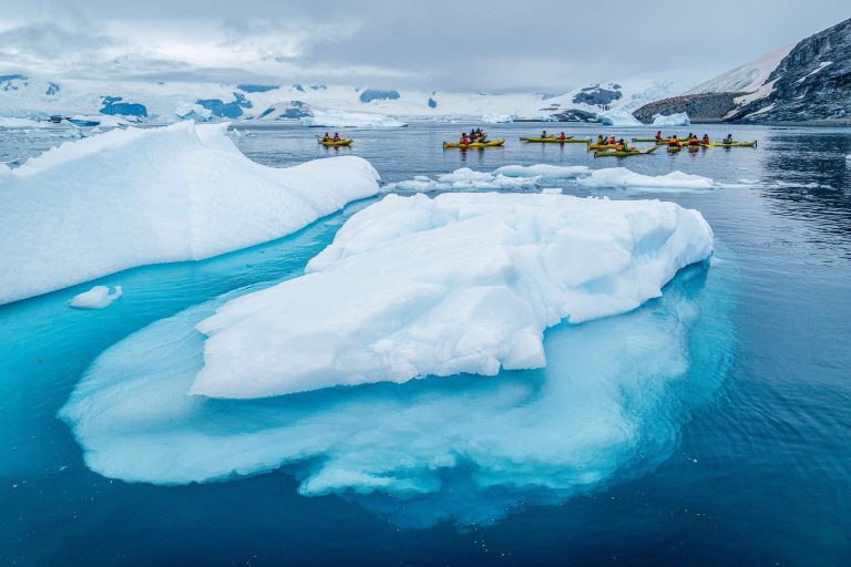 antarctica kayaking past blue icebergs qe