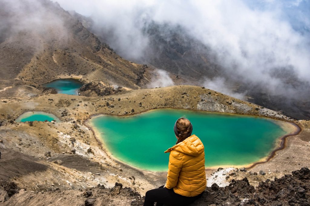 new zealand tongariro alpine crossing hiker overlooking emerald lake istk