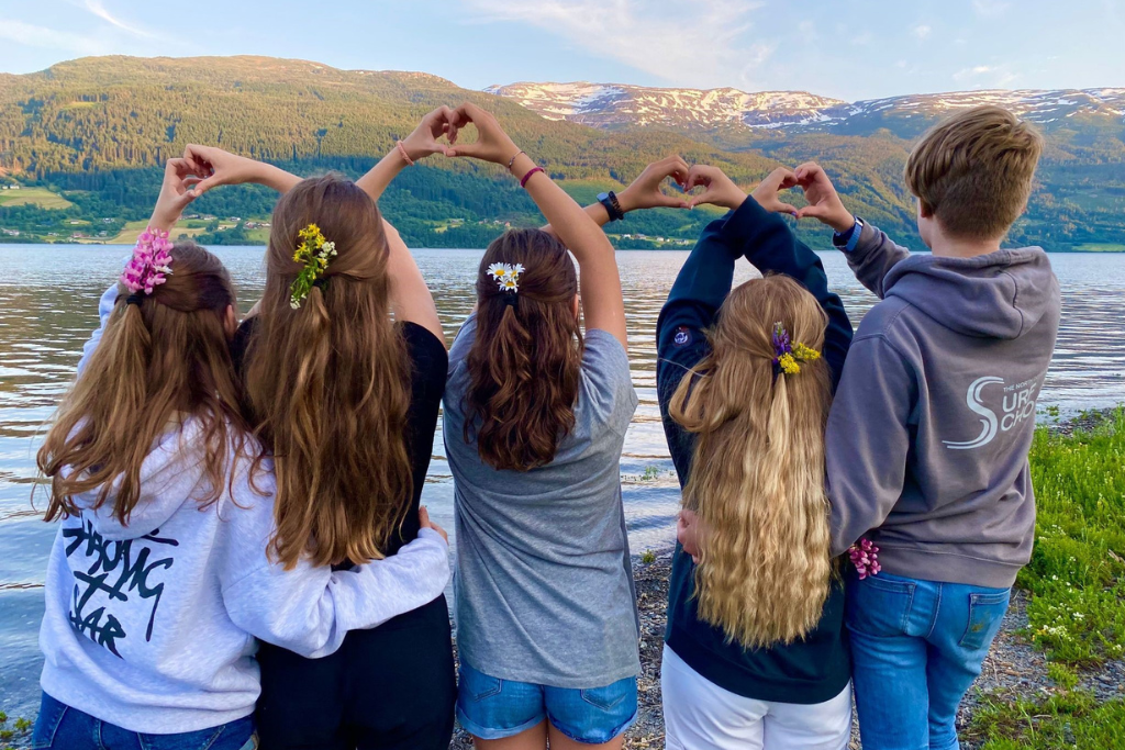 Picture of children making hearts with their hands with Voss river in Norway in the background