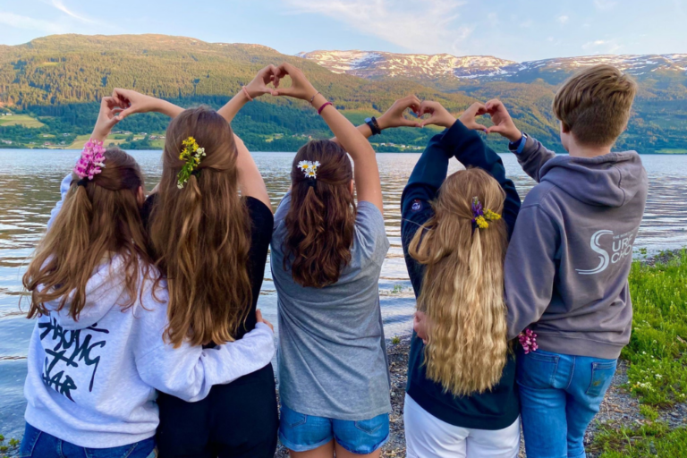 Picture of children making hearts with their hands with Voss river in Norway in the background