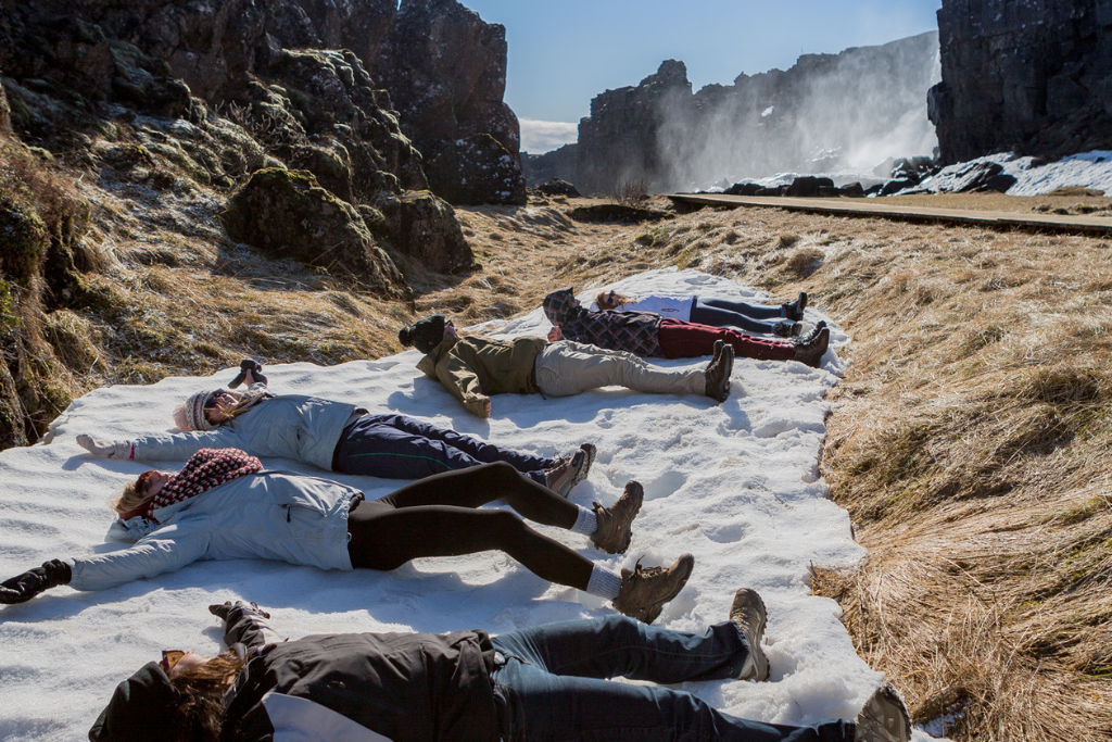 Picture of students lying down on a snowy cliff on a school trip