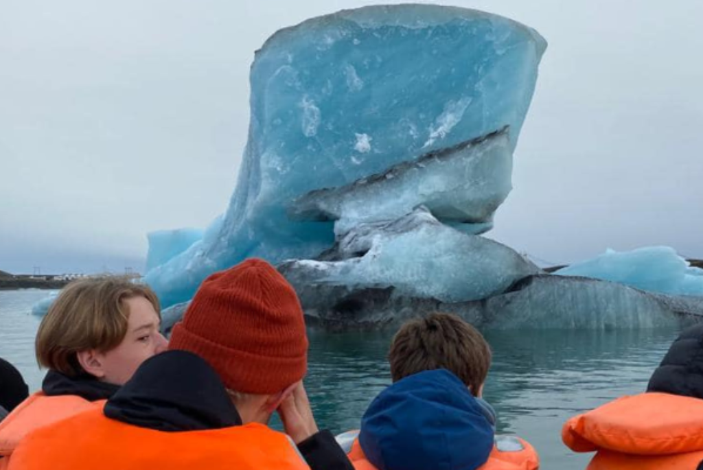 Picture of students with a large iceberg in the background